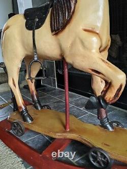 VINTAGE HANDCRAFTED WOODEN ROCKING HORSE with cast iron wheels & leather saddle
